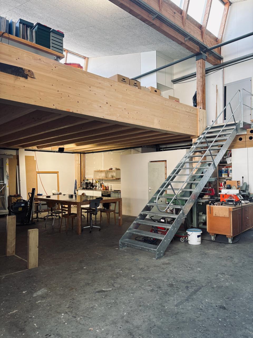Atelier d'architecture avec structure en bois, escalier métallique et postes de travail